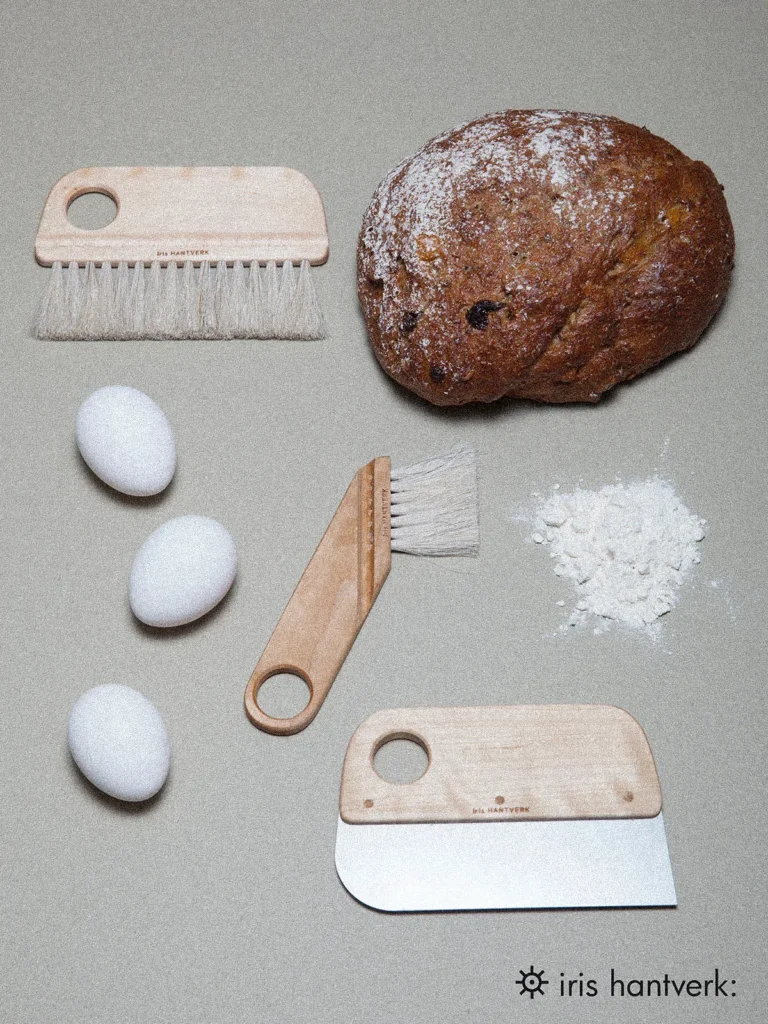 Iris Hantverk Backbürsten und Teigschaber aus Holz – Nachhaltige Küchenhelfer mit frisch gebackenem Brot und Eiern.