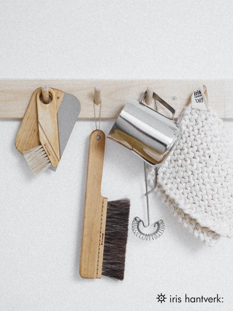 Iris Hantverk: Küchenutensilien an einer Holzleiste – Handgefertigte Bürsten, Topflappen und nachhaltige Küchenhelfer aus natürlichen Materialien.